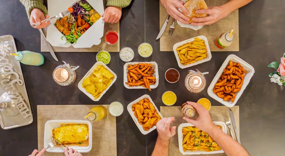 Tisch mit Pommes, Sweet Potato Fries und Bowls zum Teilen