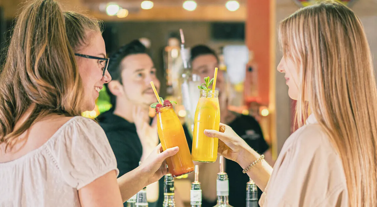 Gäste stoßen an der Bar mit Cocktails an
